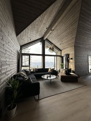 Un salon moderne avec une grande fenêtre, un canapé, une table basse et une plante en pot.