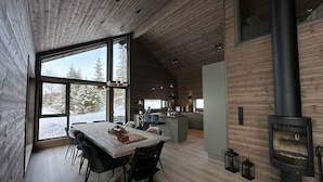 A modern interior with a dining area, kitchen, and a wood-burning stove.