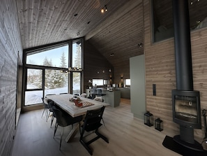 A modern interior with a dining area, kitchen, and a wood-burning stove.