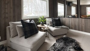 A modern living room with two sofas, a round side table, a mirror, and a large window with a view of trees. - Newly renovated house close to everything (Hol)