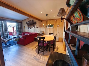 Una habitación acogedora con un sofá rojo, una mesa de comedor de madera y sillas.