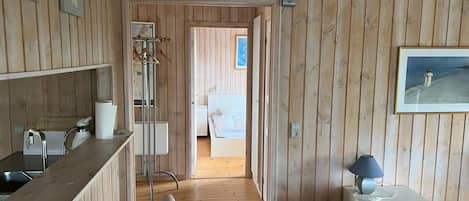 A wooden-paneled room with a bed, bedside table, and a framed picture on the wall.