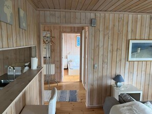 Ein Zimmer mit Holzwänden, einem Bett, einem Nachttisch und einem gerahmten Bild an der Wand.