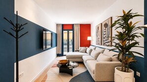 Uma sala de estar moderna com um sofá, uma mesa de centro, uma planta e obras de arte na parede.