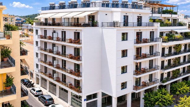 Um hotel com vários andares, varandas, área externa para sentar e terraço no telhado.