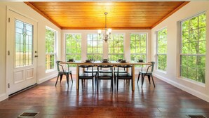 A dining room with a wooden ceiling, large windows, and a table set for four. - *Spacious 5BD w/ Hot Tub | FirePit + Fireplaces* (Sevierville)