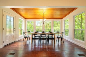 A dining room with a wooden ceiling, large windows, and a table set for four. - *Spacious 5BD w/ Hot Tub | FirePit + Fireplaces* (Sevierville)