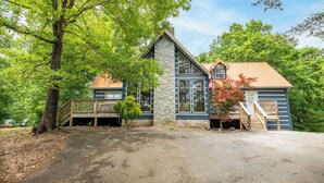 A two-story house with a stone facade, a wooden deck, and a covered porch. - *Spacious 5BD w/ Hot Tub | FirePit + Fireplaces* (Sevierville)