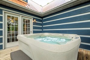 A hot tub on a wooden deck with a house featuring blue and white siding. - *Spacious 5BD w/ Hot Tub | FirePit + Fireplaces* (Sevierville)