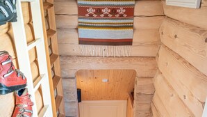 Una escalera de madera que lleva a una puerta, con un zapatero a la izquierda y un tapete estampado en la parte superior.