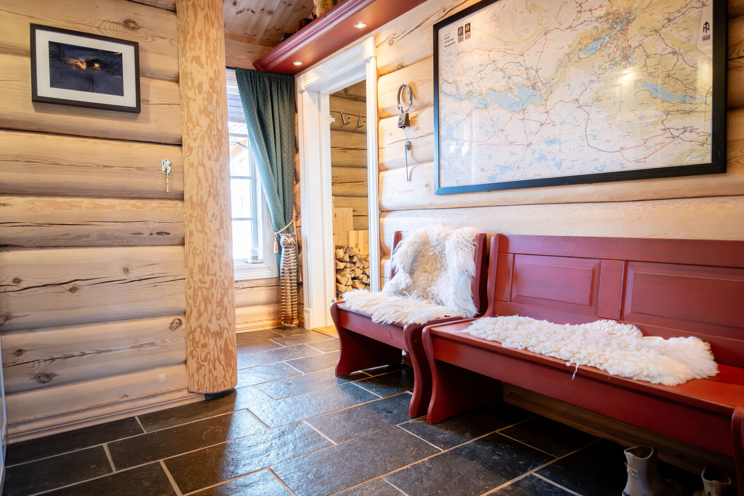 A log cabin interior with a red bench, a map on the wall, and a framed picture.