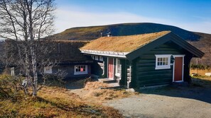 Une cabane en rondins avec un toit de chaume, une porte rouge et une fenêtre sur laquelle est inscrit le numéro « 212 ».