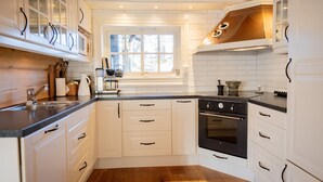 Una cocina con armarios blancos, encimera negra y horno.