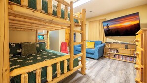A bunk bed room with a television, a bookshelf, and a couch. - *Relaxing 3BD w/ Hot Tub | FirePit + Pool Access* (Gatlinburg)
