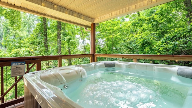 A hot tub with a wooden deck and a view of a forest. - *Relaxing 3BD w/ Hot Tub | FirePit + Pool Access* (Gatlinburg)