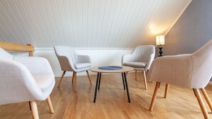 Quarto com teto inclinado, uma mesa redonda com cadeiras e um abajur.