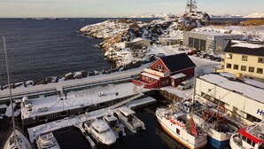 Uma marina costeira com barcos atracados, um edifício vermelho e uma torre de comunicação.