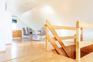 Een modern interieur met een eethoek, een houten trap en een keuken op de achtergrond.
