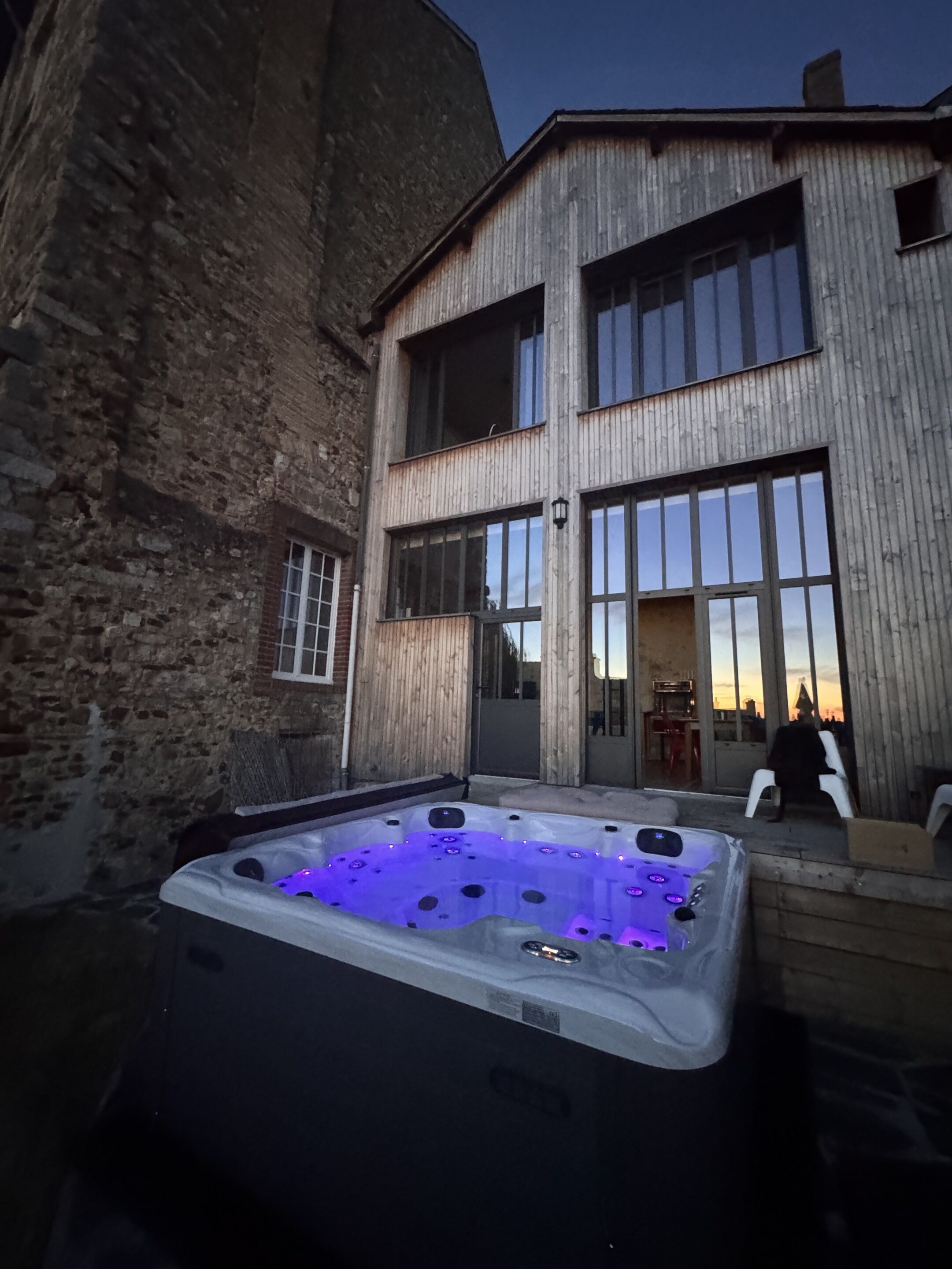 Un área de spa con un jacuzzi y un edificio de grandes ventanales.