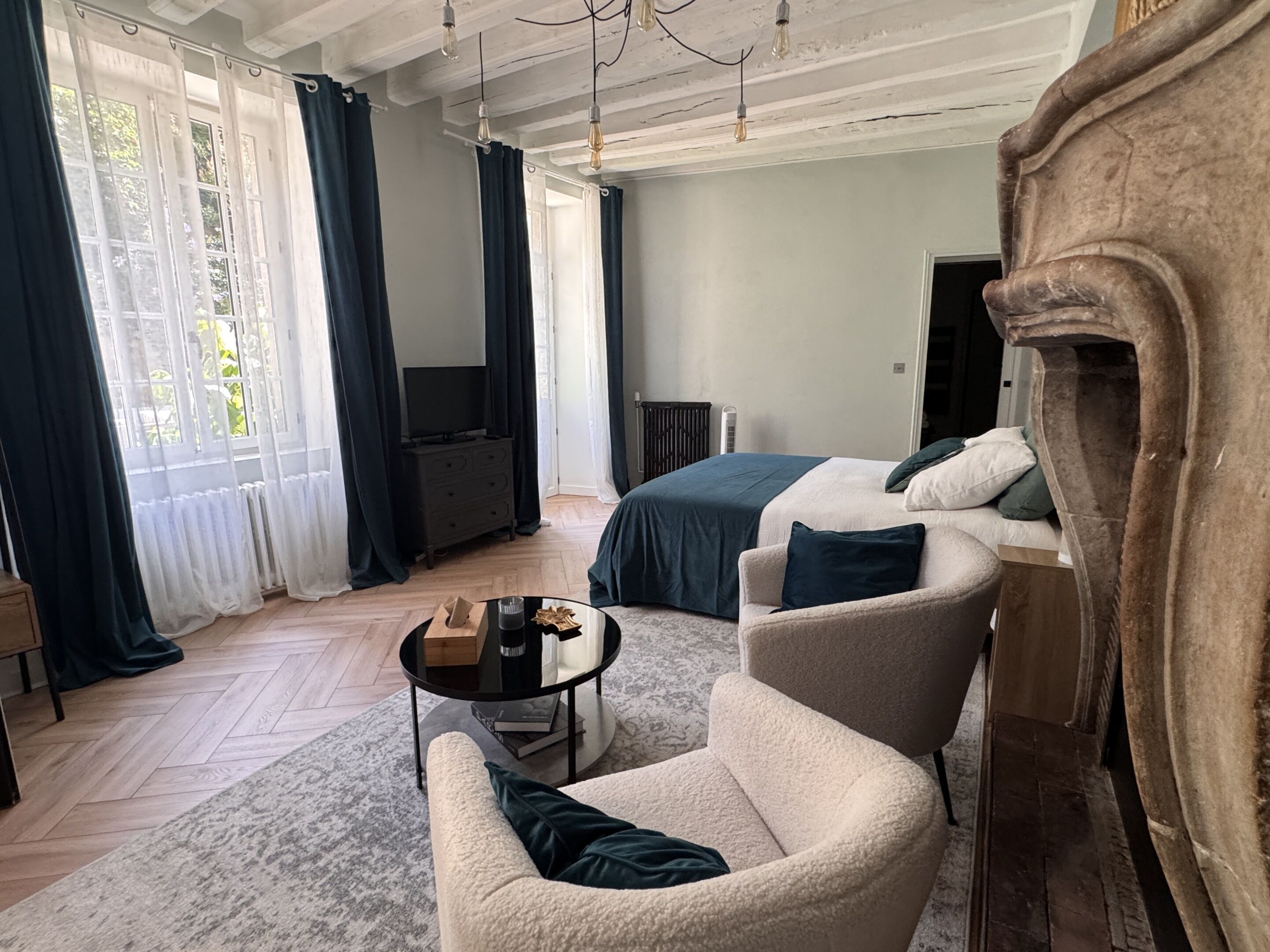 A modern room with a bed, a chair, a table, and a fireplace.