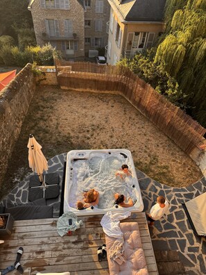 A hot tub surrounded by stone walls and a wooden deck with lounge chairs.