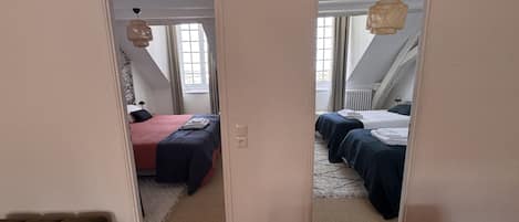 Une chambre avec deux lits, une fenêtre et un ventilateur de plafond.