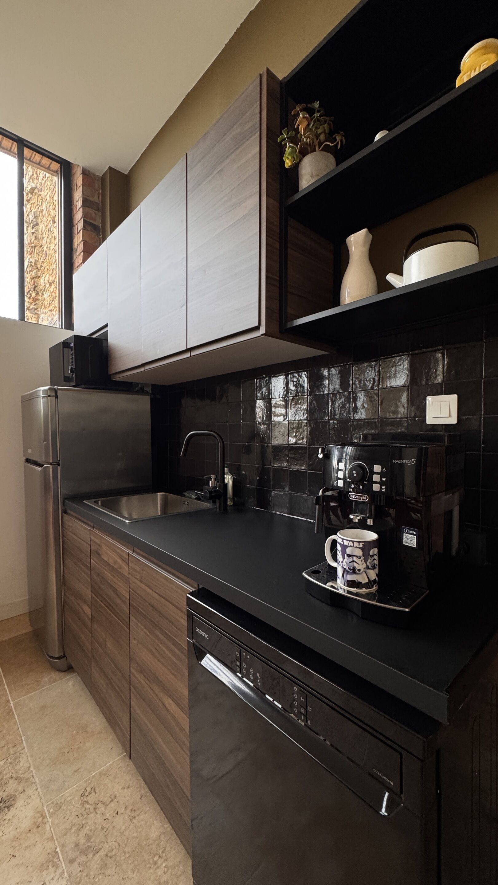 A modern kitchen with a dishwasher, a coffee maker, and a microwave.
