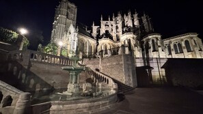 Un edificio histórico con arquitectura gótica, una fuente central y una gran escalera que conduce a la entrada.