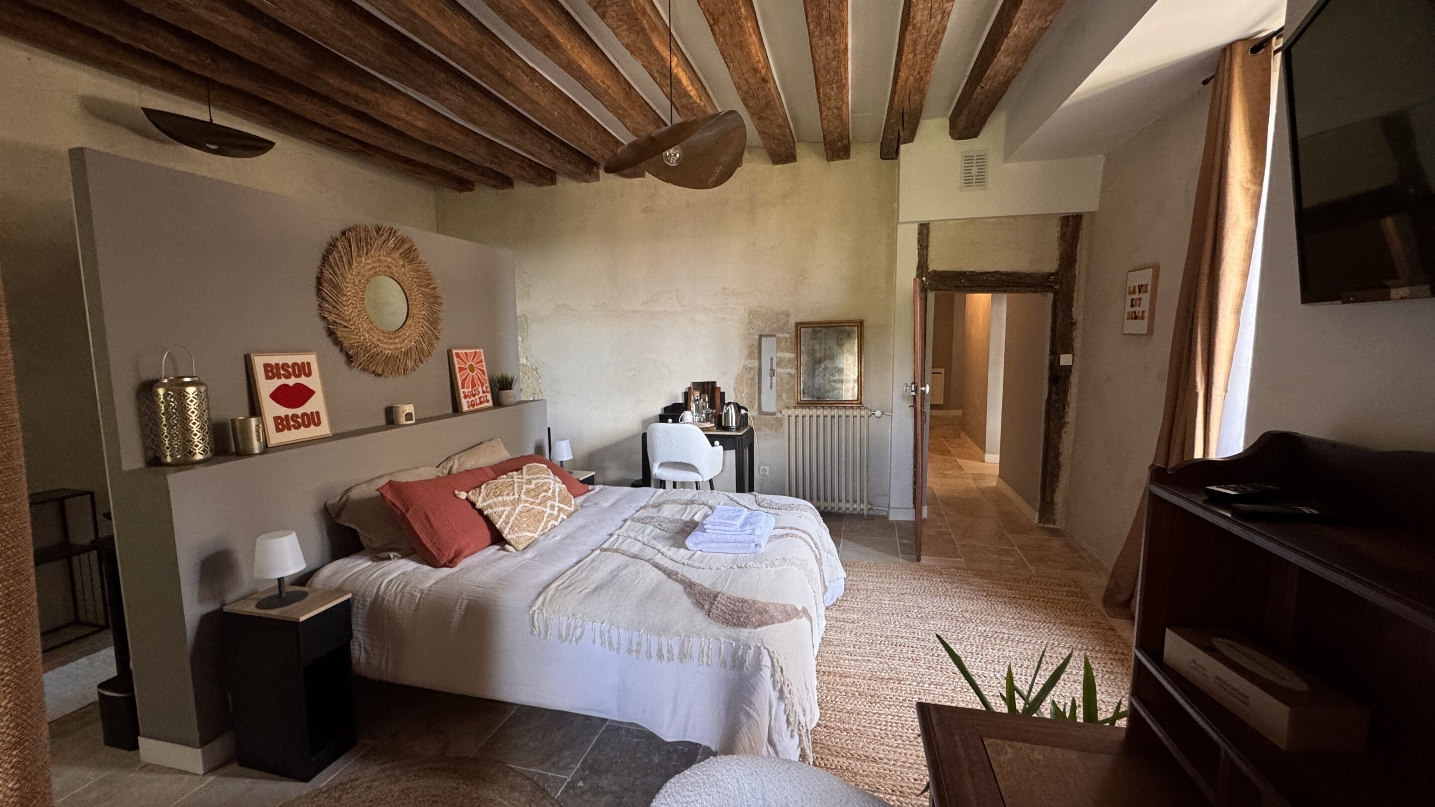 A bedroom with a bed, bedside table, lamp, and a mirror on the wall.