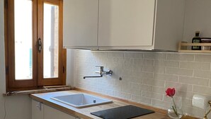 Een keuken met witte kasten, een houten aanrecht, een gootsteen en een raam met uitzicht.