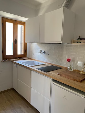 Una cocina con armarios blancos, encimera de madera, un lavamanos y una ventana con vistas.