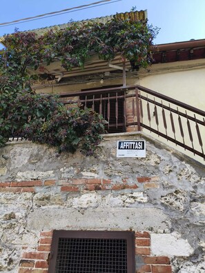 Fachada de edificio con un letrero que dice 'AFFITTAZI' y una reja metálica.