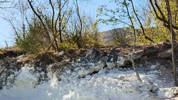 Een natuurlandschap met een waterpartij, rotsachtig terrein en schaarse begroeiing.