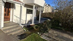 A residential building with a front porch, steps, and a small garden area. - Central loft with parking in Bergen (Bergen)