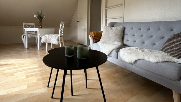 A modern loft bedroom with a sloped ceiling, a grey sofa, a round black coffee table, and a white chair. - Central loft with parking in Bergen (Bergen)