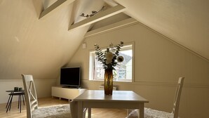 A room with a sloped ceiling, a dining table with chairs, a TV, and a window with a view. - Central loft with parking in Bergen (Bergen)