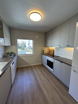 A kitchen with white cabinets, a window, and a built-in oven. - Central 3 bedroom apartment with parking (Bergen)