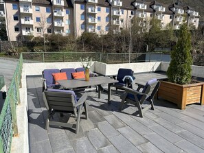 Una terraza en la azotea con muebles de exterior, una mesa y una jardinera.