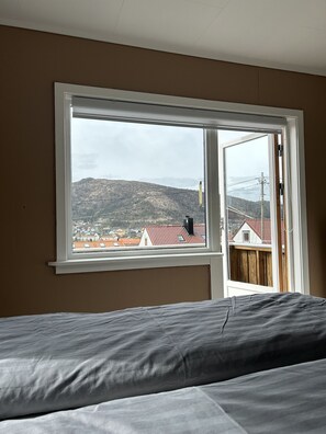 A bedroom with a bed, a window, and a view of a hilly landscape with houses. - Central Apartment with parking, Bergen (Bergen)