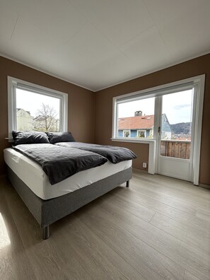 A bedroom with a bed, two windows, and a view of houses. - Central Apartment with parking, Bergen (Bergen)