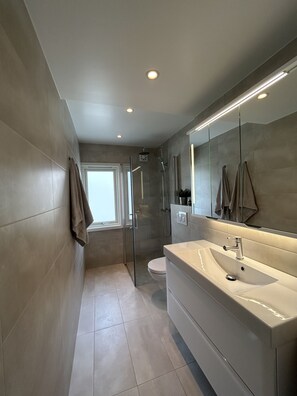 Une salle de bain moderne avec un grand miroir, un lavabo et une douche.