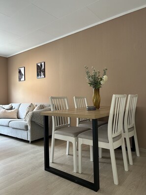 A dining area with a round table, white chairs, a sofa, and two framed pictures on the wall. - Central Apartment with parking, Bergen (Bergen)