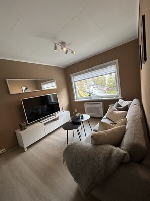 A living room with a TV, sofa, coffee table, and a window with a view. - Central Apartment with parking, Bergen (Bergen)