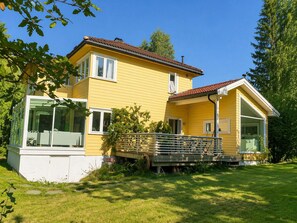 Ett tvåvåningshus med gul fasad, en balkong, stora fönster och ett rött tak.