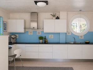 A modern kitchen with white cabinets, a round window, and blue tiles. - Spacious Villa in Lillehammer (Lillehammer)
