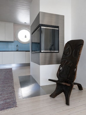 A modern kitchen with a built-in oven, a round window, and a dark wooden chair. - Spacious Villa in Lillehammer (Lillehammer)