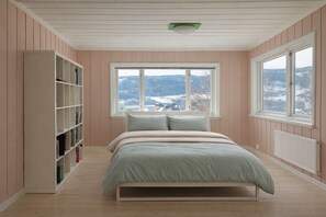 Une chambre à coucher avec un lit, une bibliothèque et de grandes fenêtres.