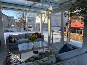 A conservatory with a glass ceiling, a grey sofa, a coffee table, and a vase with flowers. - Spacious Villa in Lillehammer (Lillehammer)