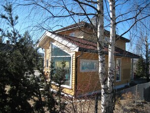 Une maison à deux étages, dotée d’un toit à pignon, de grandes fenêtres et d’une cheminée bien visible.