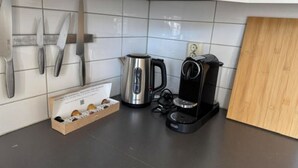 Eine Küche mit Kaffeemaschine, Wasserkocher und Messern an der Wand.